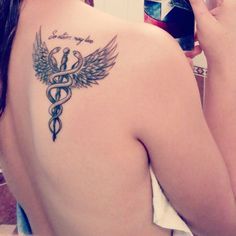 the back of a woman's shoulder with a tattoo on it and a medical symbol