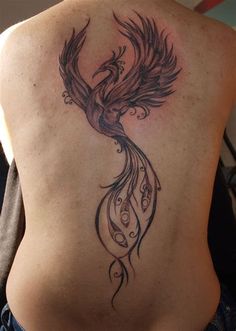 a woman's back with a bird tattoo on her left side ribcage