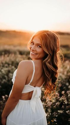 a woman standing in a field smiling at the camera