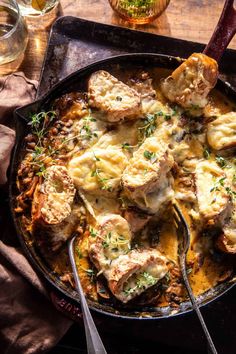 a skillet filled with meat and cheese covered in gravy on top of a wooden table