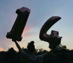 a woman holding up two large balloons in the air