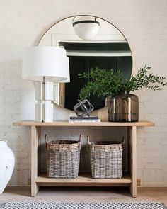 a table with two baskets and a mirror on it in front of a white brick wall