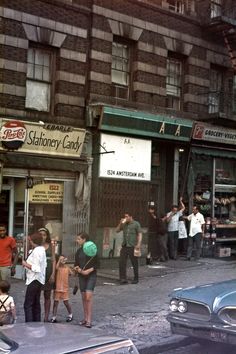 an old photo of people standing in front of a store on the corner of a city street