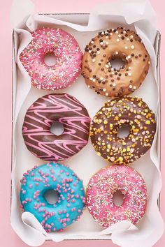 six donuts in a box with sprinkles on them