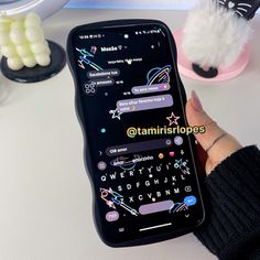 a person holding a cell phone with stickers on the screen next to other items