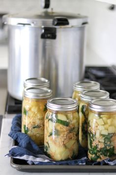 four jars filled with food sitting on top of a stove