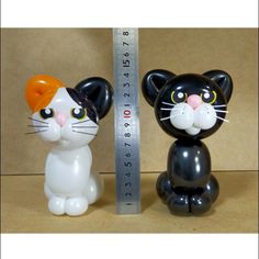 two black and white cat figurines next to a measuring tape