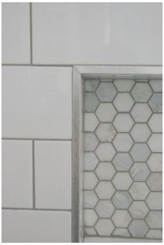 the corner of a bathroom with white tile and hexagonal pattern on it's walls