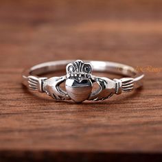 a silver cladder's heart ring on top of a wooden table