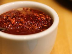 a white bowl filled with sauce on top of a wooden table