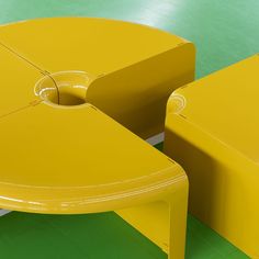 two yellow tables sitting next to each other on a green floor