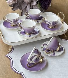 purple and white porcelain tea set with matching saucers, cups and saucers on a tray