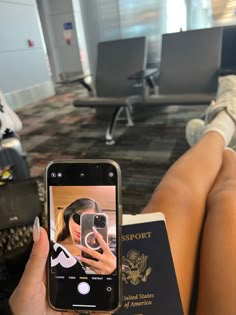 a person is taking a selfie with their cell phone while sitting in an airport