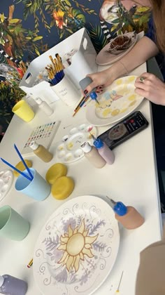 a woman sitting at a table painting on plates