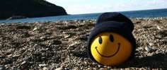 a smiley face ball laying on top of a rocky beach