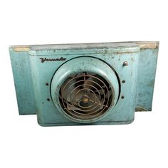 an old blue box fan sitting on top of a white wall next to a power cord