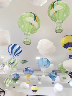 many colorful hot air balloons are floating in the sky above a room with white walls