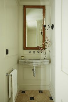 a bathroom with a sink, mirror and towel rack on the wall next to it