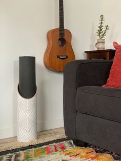 a living room with a guitar on the wall next to a couch and floor lamp