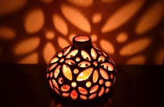 a lit candle holder sitting on top of a table next to a shadow cast wall