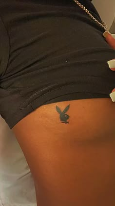 a woman with a bird tattoo on her lower back, showing it's stomach