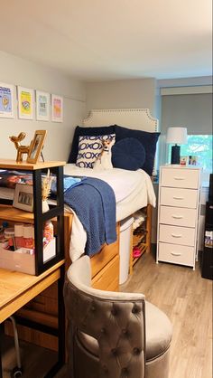 a bedroom with a bed, desk and chair in it's center area next to a window