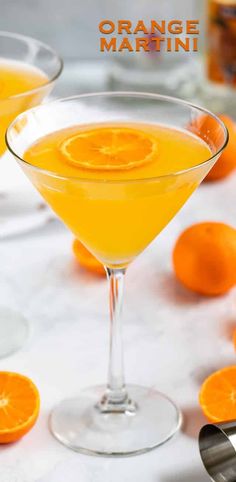 two martini glasses filled with orange juice and garnished with an orange slice on the rim