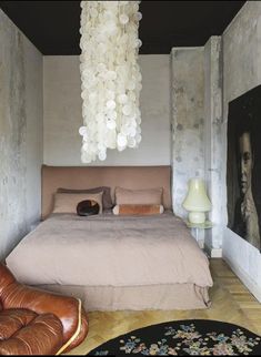 a bedroom with a bed, chair and chandelier in front of a painting on the wall