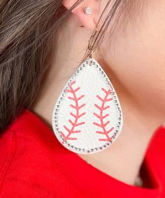 a close up of a person wearing earrings with baseball stitching on the back of them