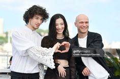 three people standing next to each other and making a heart shape with their hands stock photo