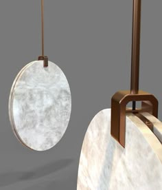 two marble and metal objects are hanging from the ceiling, one with a round object on it