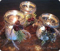 three glass jars filled with candles on top of a wooden table