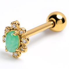 a gold nose piercing with green stone surrounded by white stones on it's end