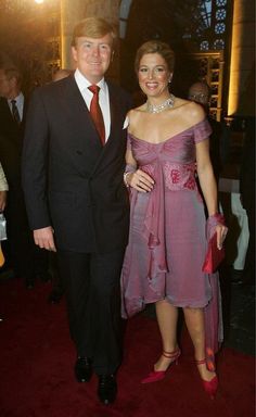 a man in a suit and tie standing next to a woman on a red carpet