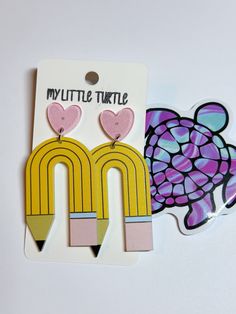 two pieces of art that are shaped like pencils and heart shapes, one has a turtle on it