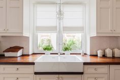 a kitchen with white cabinets and wooden counter tops, an open window above the sink