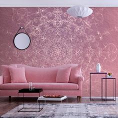 a living room with pink couches and wallpaper on the walls, along with a round mirror