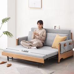 a woman sitting on top of a couch next to a plant