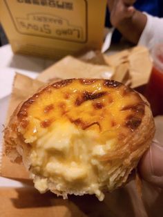 a person holding up a pastry with cheese on it