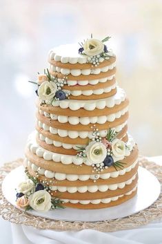 a three tiered wedding cake with white flowers on the top and sides is sitting on a lace doily