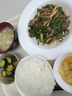 a plate with rice, meat and vegetables next to bowls of food on a tray