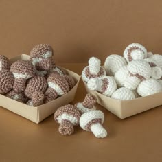 crocheted stuffed animals are in small boxes on a brown surface, next to each other