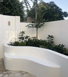 a white bath tub sitting next to a lush green tree