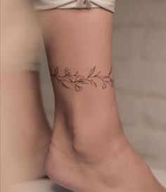 a woman's foot with a flower tattoo on the side of her leg,