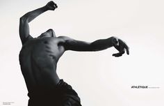 black and white photograph of a shirtless man throwing a frisbee in the air