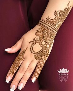 a woman's hand with henna tattoos on her arm and hands, showing the intricate