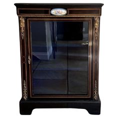 an old fashioned black and gold cabinet with glass doors on the front, side view