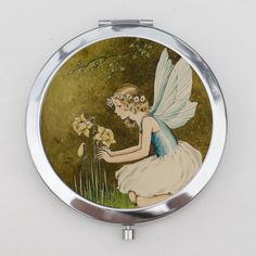 a compact mirror with a painting of a little fairy picking flowers from a flower bed