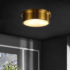 a round light fixture hanging from the ceiling in a room with dark walls and windows