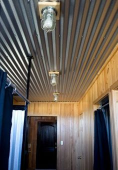 a room with wooden walls and metal roofing on the ceiling is lit by two lights